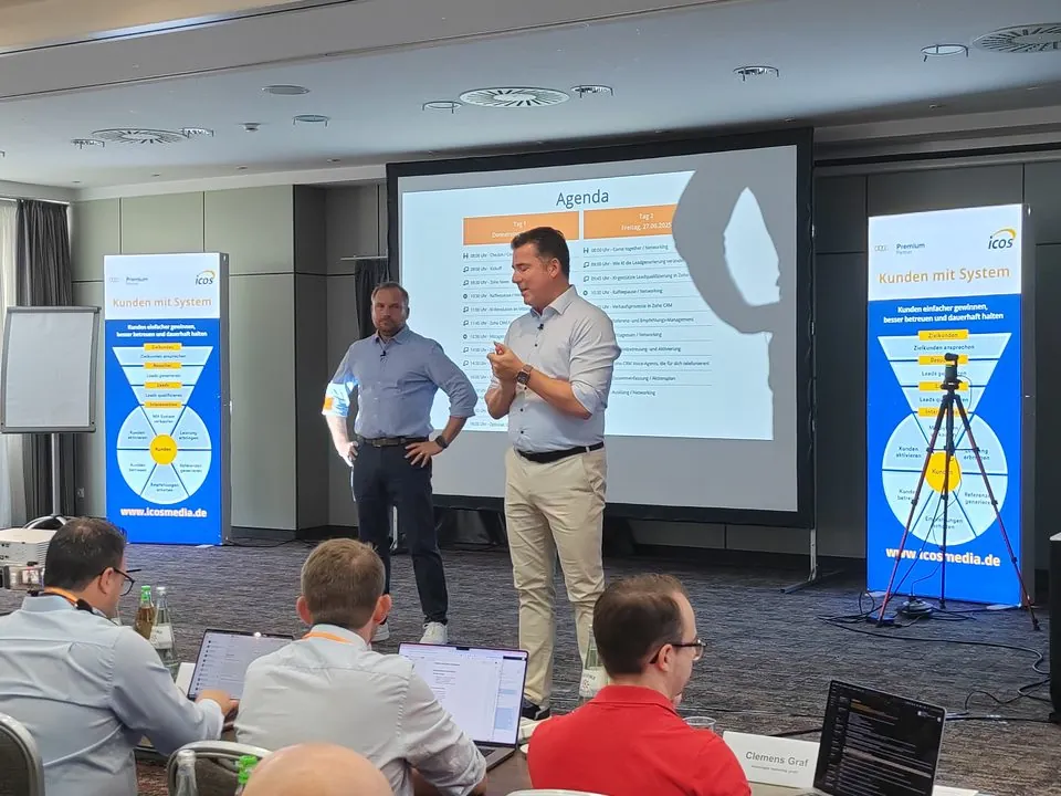 Florian und Thomas Stahl auf der Bühne der IcosMedia Zoho Days, links und rechts Aufsteller mit dem Kundensystem